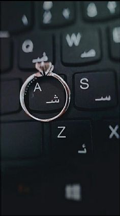 a ring sitting on top of a computer keyboard with the word love spelled in arabic