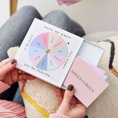 a woman is holding up a book on her couch