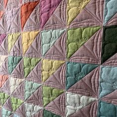 a colorful quilt is displayed on a bed