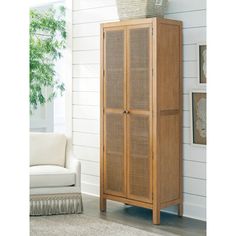 a tall wooden cabinet with wicker doors in a white living room next to a couch