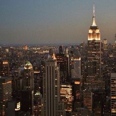 the city skyline is lit up at night with skyscrapers and other tall buildings in the foreground