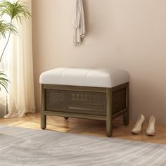 a white bench sitting in the corner of a room next to a plant and shoes