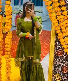 a woman taking a selfie in front of a mirror with yellow flowers around her