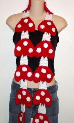 a woman wearing a red and white crocheted scarf with mushrooms on the front