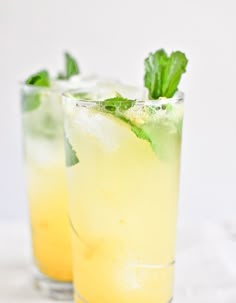 two glasses filled with lemonade and mint garnish on a white tablecloth