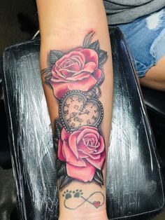 a woman's arm with roses on it and an old clock tattoo design in the middle