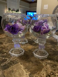 two clear glass bowls with purple flowers in them