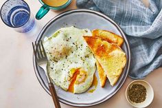 an omelet and toast on a plate next to two cups of coffee