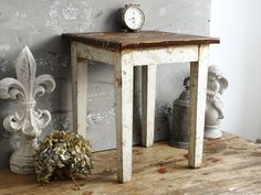 an old wooden table with a clock on it next to two vases and a plant