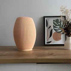 a vase sitting on top of a wooden table next to a framed photograph and flowers