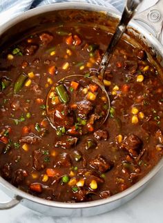 a pot full of stew with a ladle scooping up some food from it