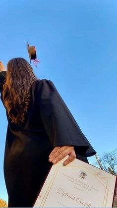 a woman in black graduation gown holding a diploma