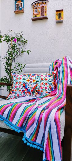 a bed with a colorful blanket on top of it next to a potted plant