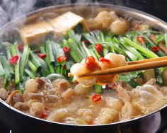 chopsticks are being used to stir food in a pan with broccoli