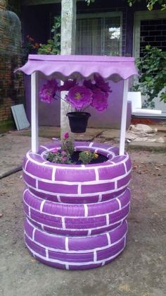 a potted plant sitting on top of a purple tire covered stand with flowers in it