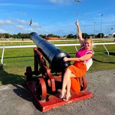 a woman sitting on top of a cannon