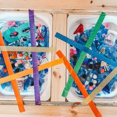 two trays filled with different colored paper and plastic beads on top of wooden boards