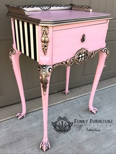 an antique pink and black striped desk with drawers on it's legs, sitting in front of a garage door