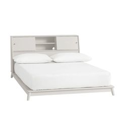 a bed with a white headboard and two pillows on it's sides, in front of a white background