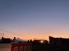 the sun is setting over some buildings and hills in the distance, as seen from an alleyway