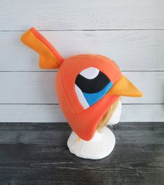 an orange bird hat sitting on top of a white mannequin head