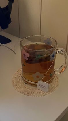 a glass mug with tea in it sitting on a table