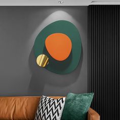 a brown leather couch sitting in front of a green and orange wall mounted art piece