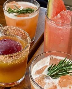 three glasses filled with different types of drinks on top of a wooden table next to watermelon slices