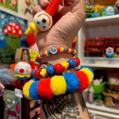 a person holding two colorful bracelets and a pen in their hand with tattoos on it