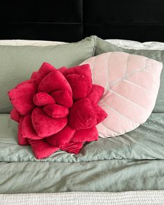 a pillow with a flower on it sitting on top of a bed next to pillows