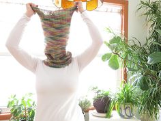 a woman holding up two pairs of glasses over her head in front of a window