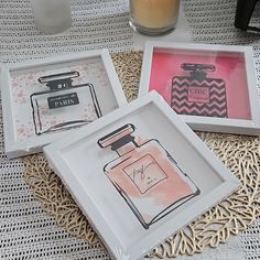 three trays with perfume bottles on them sitting on a table next to a candle