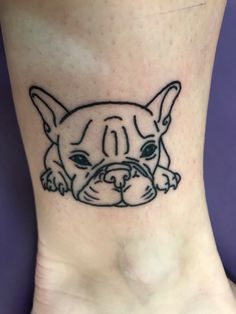 a small black and white dog tattoo on the ankle