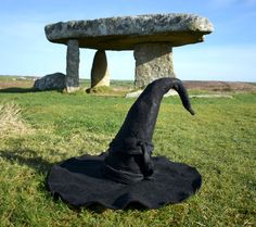 a large black hat sitting on top of a lush green field next to a stone bench