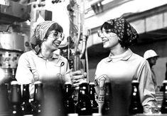 two women standing next to each other in front of bottles