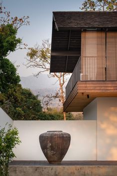 a large vase sitting on top of a cement slab in front of a building with wooden balconies