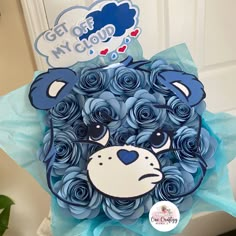 a bouquet of blue roses with a bear face on it's head in front of a door