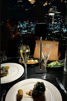 two white plates topped with food next to wine glasses