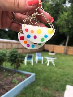 a person is holding two small polka dots on a keychain in their hand