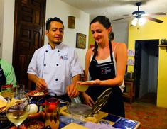 three people standing around a table preparing food