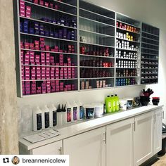 there are many bottles and containers on the wall behind the counter in this salon area