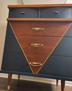 a blue and brown chest of drawers with gold trim on the top, in front of a mirror