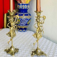 two golden candlesticks sitting on top of a table next to a blue vase