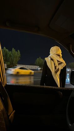 a woman sitting in the back seat of a car with a yellow taxi behind her