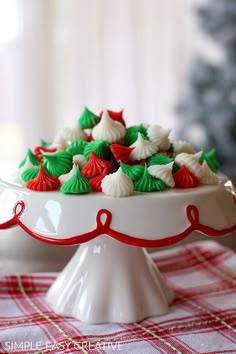 a white plate topped with green and red minis on top of a checkered table cloth