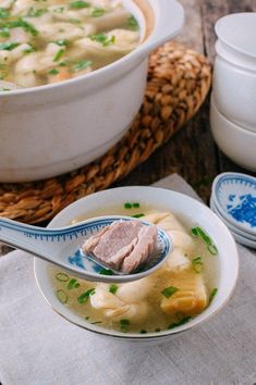 a bowl of soup with meat in it and two bowls on the table next to it