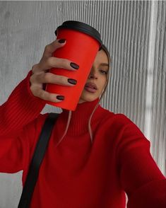 a woman in a red sweater is holding a coffee cup