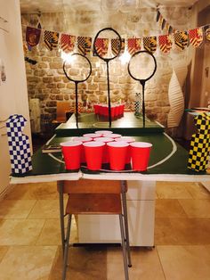 a table with red cups on it in front of a brick wall and some lights