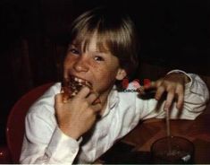 a young boy sitting at a table eating pizza