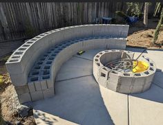 a fire pit built into the side of a concrete wall next to a wooden fence